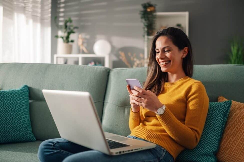 Happy woman sitting on couch because her amended tax return is being processed 