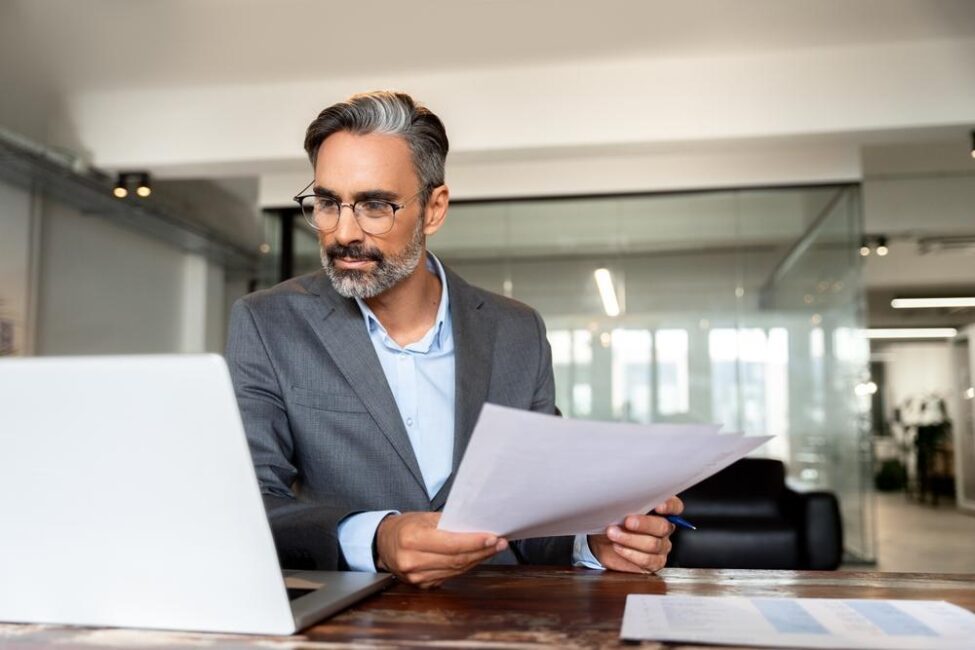 Focused man files his Schedule 1 online while handling his tax documents